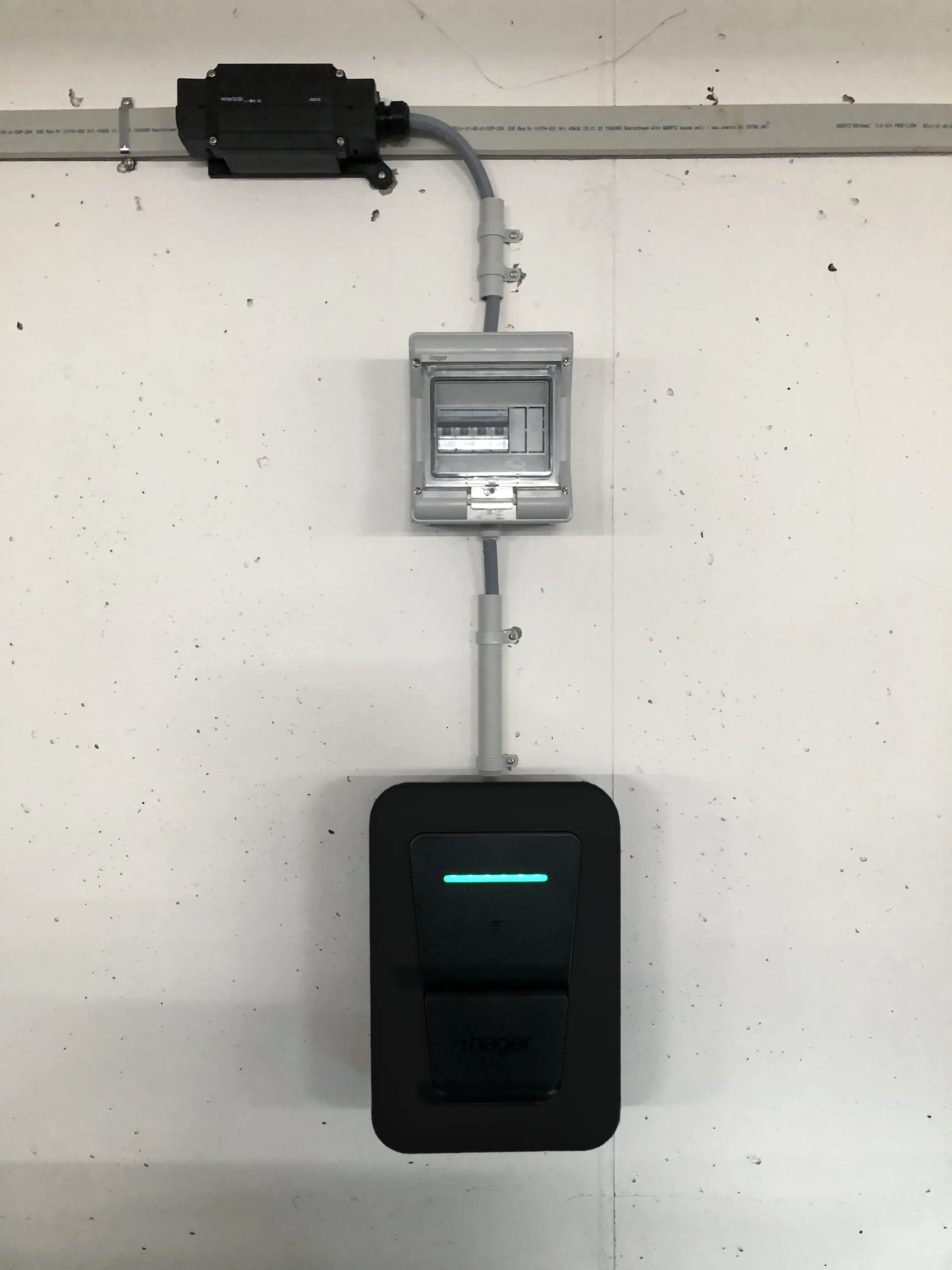 Borne de recharge Hager Witty Pro noire installée au mur sous un coffret électrique